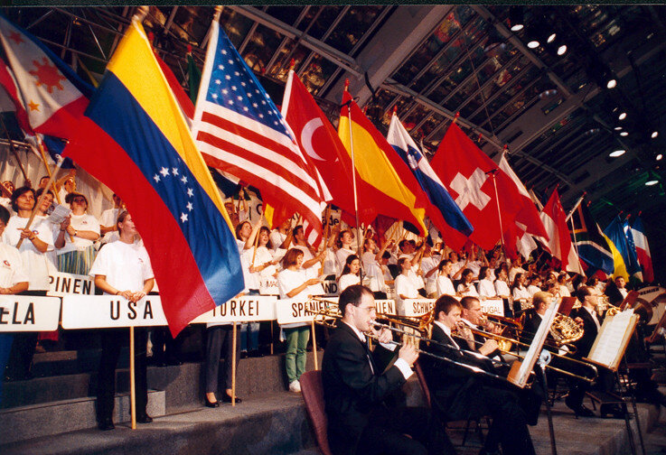 В 1997 году произошло событие, которое определило будущее киберспорта. Американец Эйнджел Муньёз основал профессиональную лигу по компьютерному спорту, которая получила название CPL (Cyberathlete Professional League). На первом турнире этой лиги, организованном в том же 1997 году, была всего одна игра — Quake. Беспрецедентный случай, когда соревнования проводились с подобной организацией: на турнире были оборудованы полноценные игровые места, за играми следили настоящие судьи и системные администраторы, а всё событие освещали журналисты.
Турнир FRAG 4 от CPL, 2000 годЗа пару лет CPL развилась в крупную франшизу. Успех лиги привлек внимание инвесторов, и в 2000 году при поддержке компании Samsung был создан своеобразный чемпионат мира по киберспорту под названием WCG (World Cyber Games). Для большинства игроков этот турнир быстро стал чем-то вроде Олимпийских игр, ведь там даже существовало понятие медальных зачетов для каждой страны по итогу соревнований. К тому же возможность отправиться в Южную Корею представлять собственную страну на мировом уровне — для 20-летних ребят это было нечто невообразимое.
Призовой фонд первого чемпионата WCG 2000 составил $200 000. Корейский город Йонъин принял 174 игрока из 17 стран мира. В качестве киберспортивных дисциплин организаторами были выбраны шутер Quake III Arena, стратегии StarCraft: Brood War и Age of Empires II: The Age of Kings, а также футбольный симулятор FIFA 2000. Фото: INTERKULTURПосле оглушительного успеха подобных мероприятий развитие киберспорта было уже не остановить. Новые турниры появлялись с каждым годом, призовые росли, организаторы искали новые способы привлечь аудиторию, благодаря чему каждый крупный чемпионат превращался в своего рода праздник, где помимо самих игр устраивались еще и настоящие шоу с участием приглашенных звезд. В мире начали появляться киберспортивные организации, которые принимали под свое крыло наиболее успешных игроков, предлагая им настоящую зарплату и комфортные условия для тренировок взамен на успешные выступления на мировой арене. Так появились легендарные MYM, Virtus.pro, Fnatic, Ninjas in Pyjamas, Mibr и десятки других клантегов, которые существуют (или существовали) на протяжении многих лет.