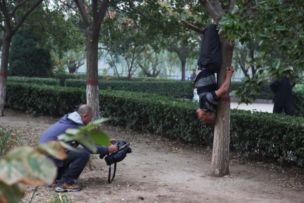 Китайский дедушка делает упражнение на дереве вниз головой. Какой молодец!