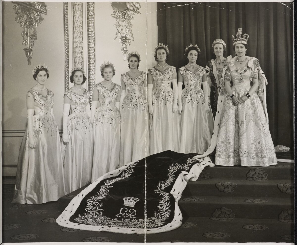 Королева Елизавета II и ее фрейлины, 1953 год. На этой фотографии видно коронационное платье Елизаветы, которое было разработано Норманом Хартнеллом, дизайнером, которому Королева и Королева-мать (мать Елизаветы) отдавали предпочтение вплоть до его смерти в 1979 году.
Платье выполнено из белого атласа с золотыми кристаллами, бриллиантами и жемчугом, и украшено изображениями уэльского лука-порея, чертополоха Шотландии, трилистника Ирландии и английской розы Тюдоров, представляющие четыре нации Великобритании. 

