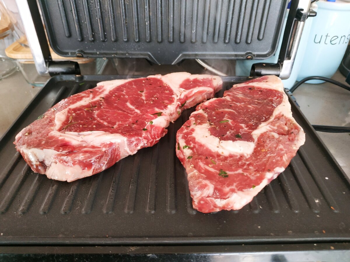 На разогретый электрогриль положили стейки.