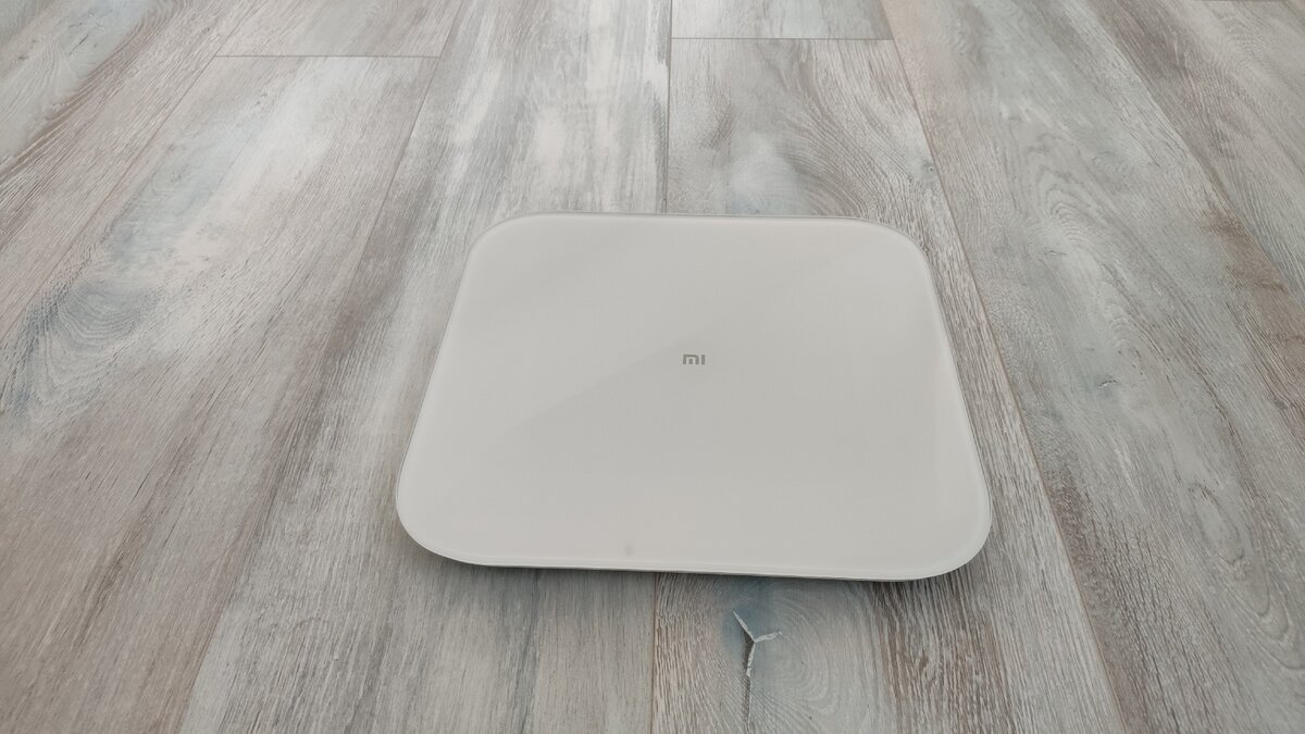 Лицевая сторона Xiaomi Mi Smart Scale 2. В выключенном состоянии видно только логотип. 