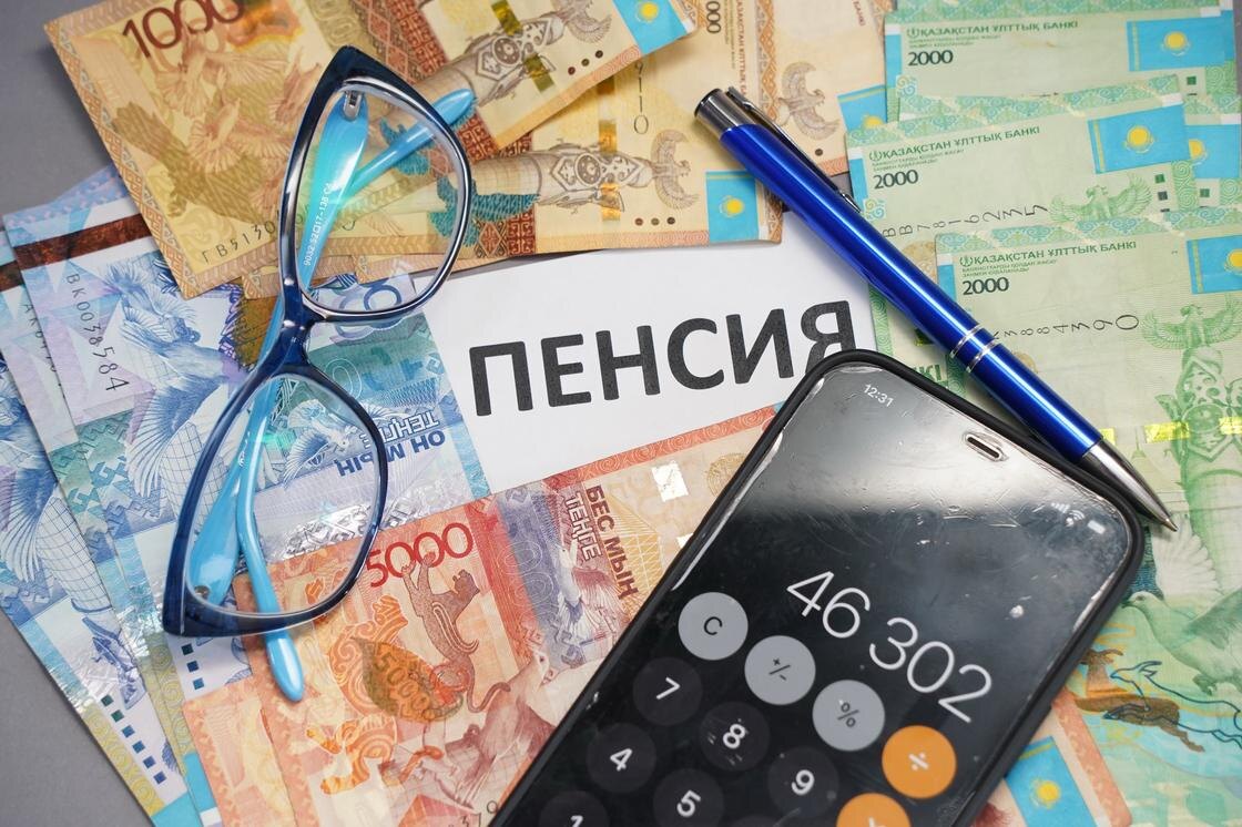    Смартфон ручка и очки лежат на купюрах тенге:NUR.KZ/Владимир Третьяков