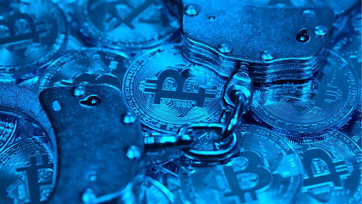 Фотография монет Bitcoin и наручников, демонстрация сдерживания криптовалют.