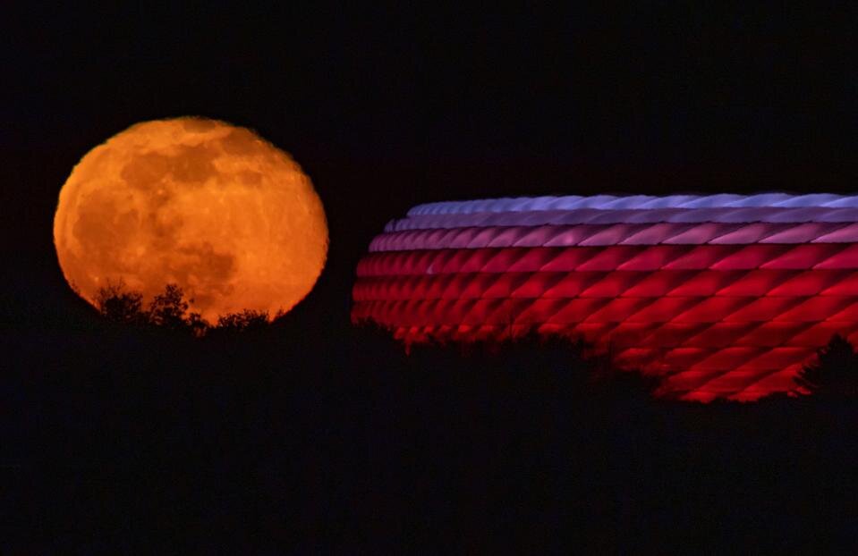 Луна встает за освещенной ареной Allianz Arena в Мюнхене, Германия. Фото: Питер Кнеффель