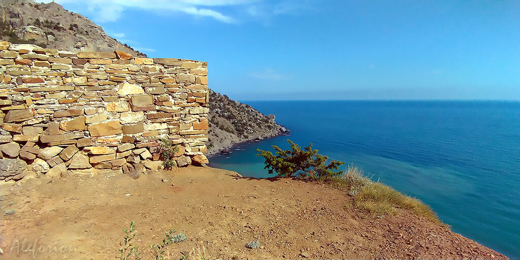 Угол восточной стены загораживает начало тропы по Караул-Обе, там находится рукотворная каменная кладка, просевшая под весом ползущего вниз склона горы. От мыса, выходящего в море, начинается Боспорская бухта.