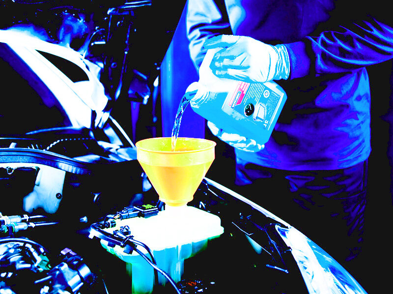 На фото изображен процесс залива охлаждающей жидкости в систему охлаждения автомобиля.