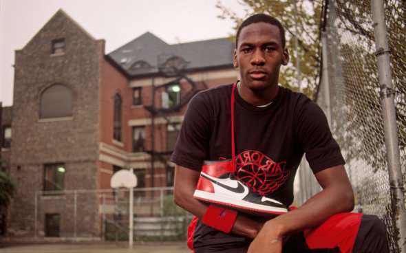 Майкл Джордан позирует рядом со своими кроссовками Air Jordan.