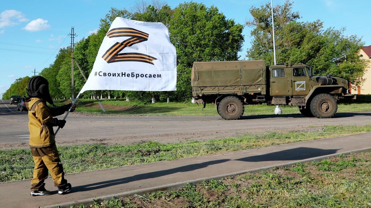    Восьмилетний мальчик Алеша приветствует проезжающие мимо российские военные автомобили в селе Веселая Лопань в Белгородской области© РИА Новости / Таисия Лисковец