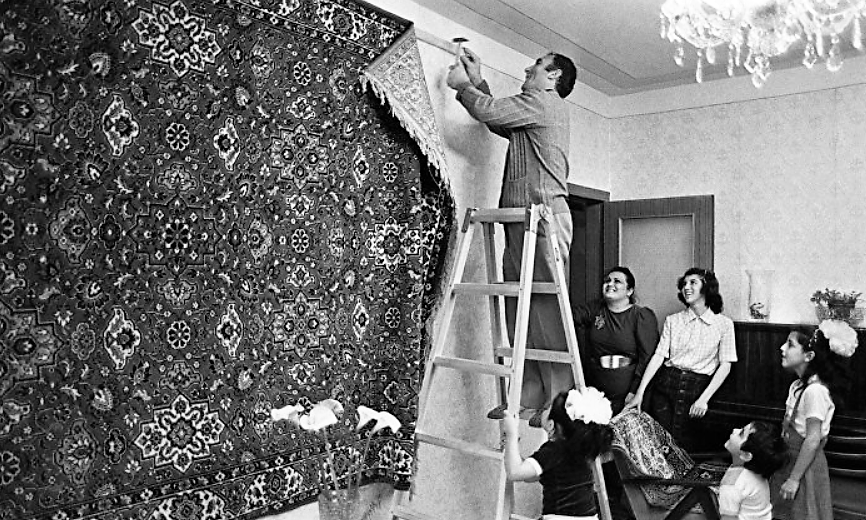 Глава семьи вешает ковер на стену