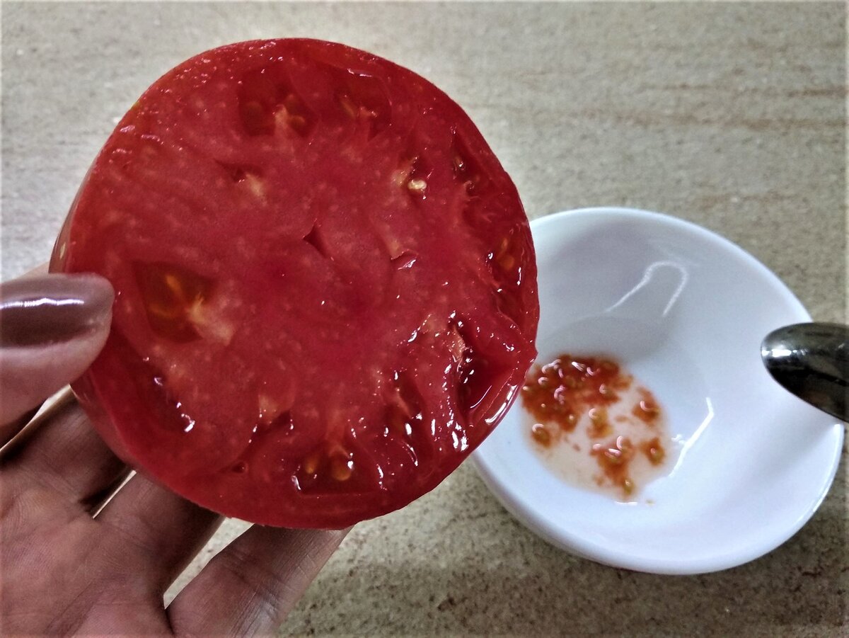 Разрезаю помидор поперек и ложкой выбираю семена в миску.