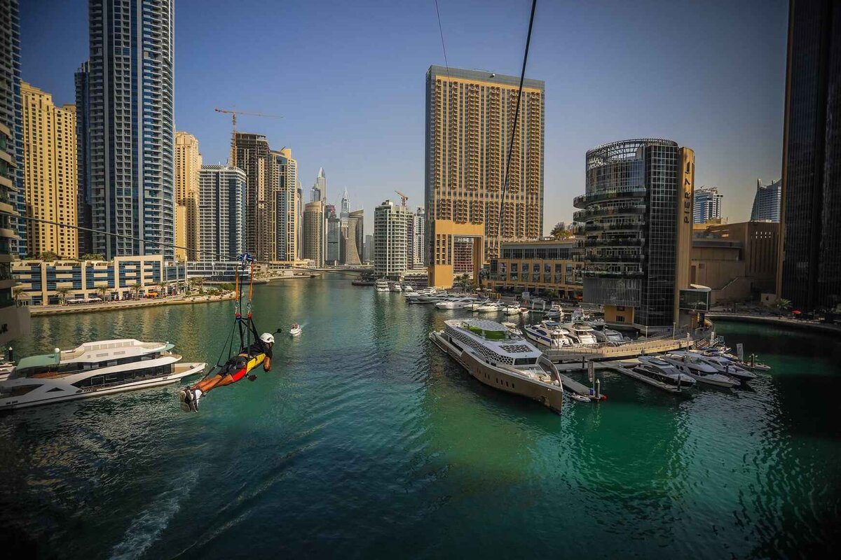 Зиплайн в Дубае (XLine Dubai Marina) считается самым быстрым, крутым и протяженным в мире. Что такое зиплайн? Это скоростной спуск по стальному тросу при помощи специального устройства, которое с одной стороны крепится к этому тросу, а с другой — к удерживающему устройству и ремням безопасности.