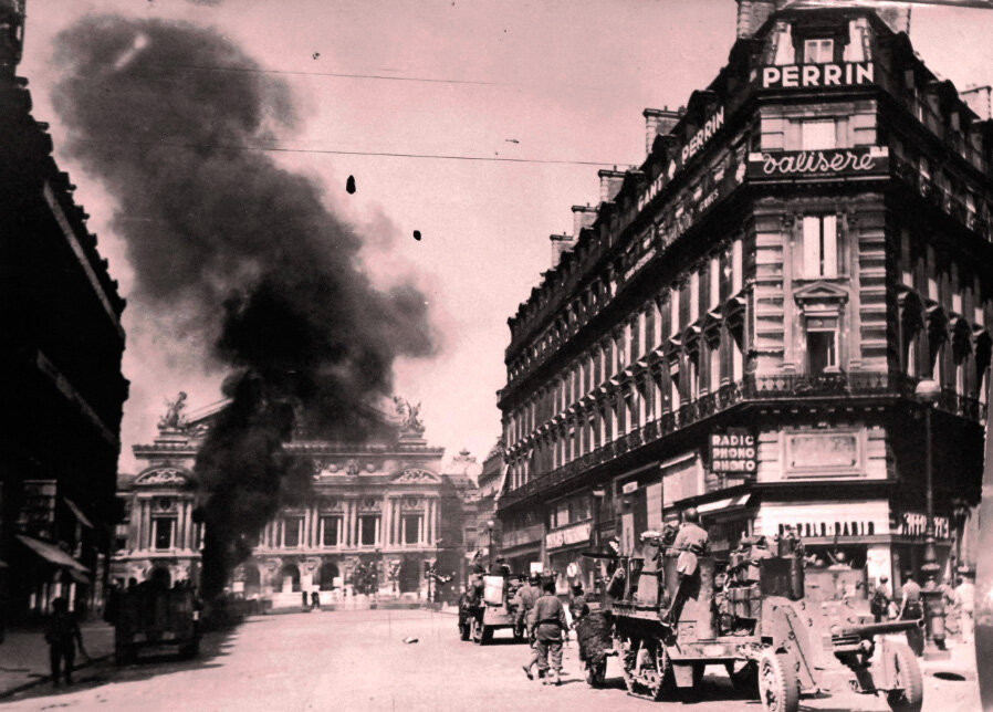 Освобождение Парижа, Франция, 25 августа 1944 года. Бронетехника дивизии Леклерка ведёт бой перед зданием Оперы. Один немецкий танк, подбитый ею, уже горит.