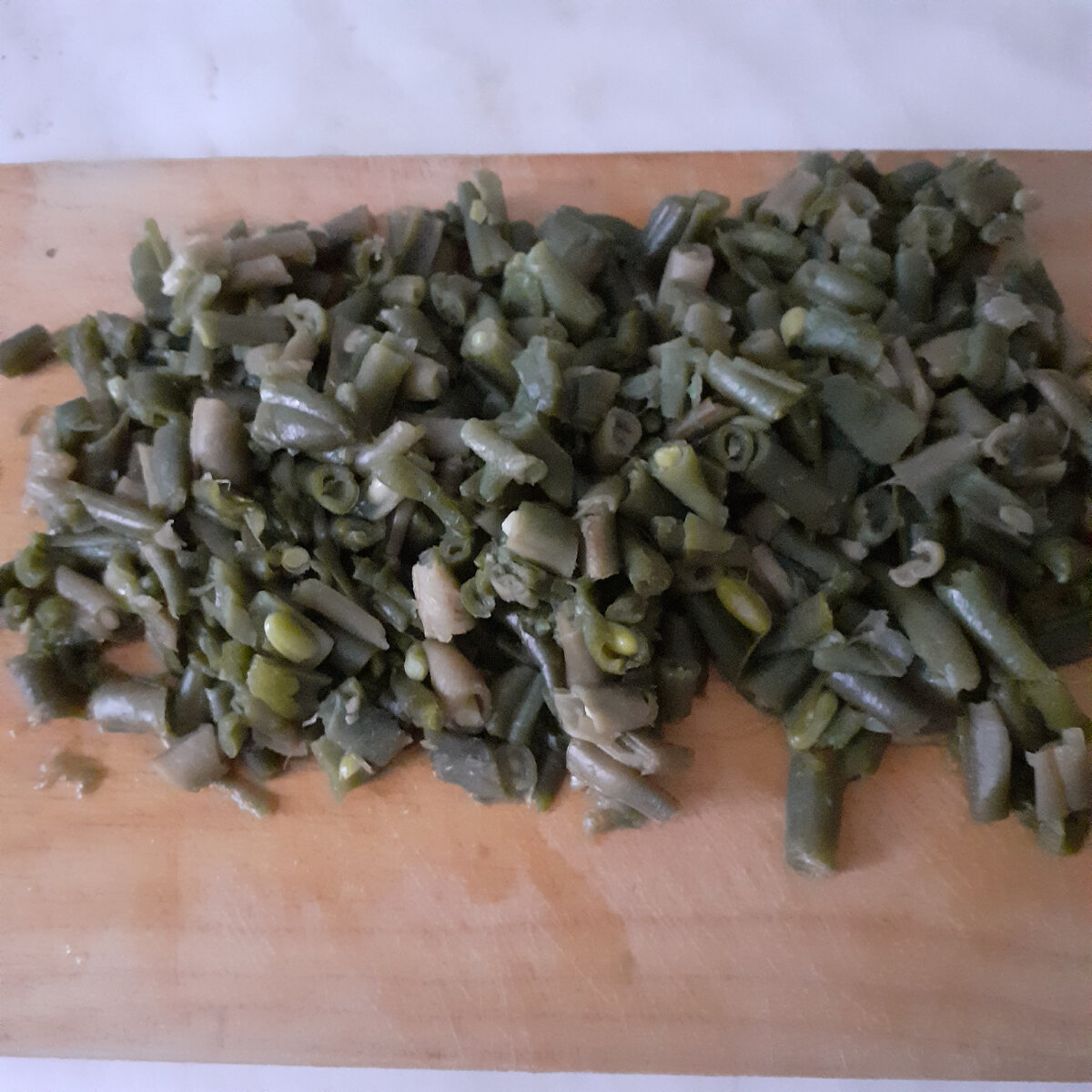 Отварить в подсоленной воде 400 г стручковой фасоли и нарезать.