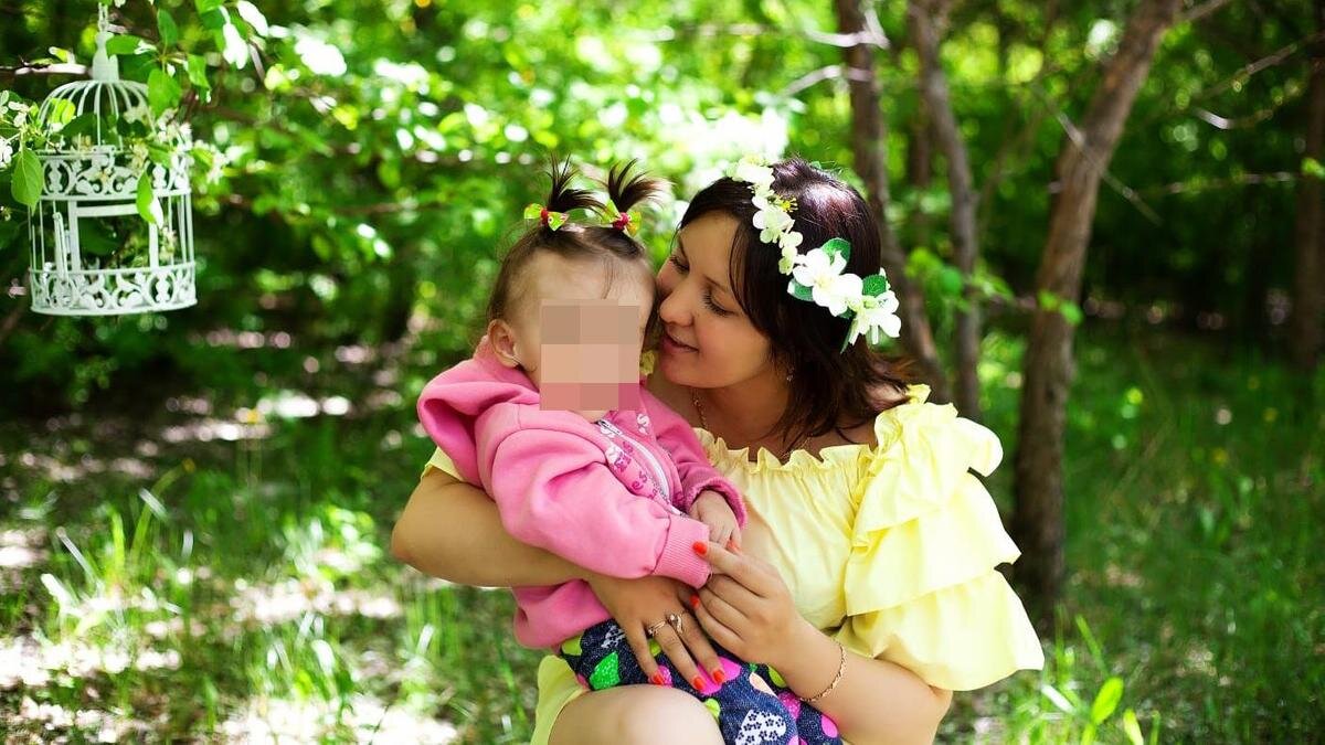    Мама с дочкой на руках гуляют в саду:из личного архива