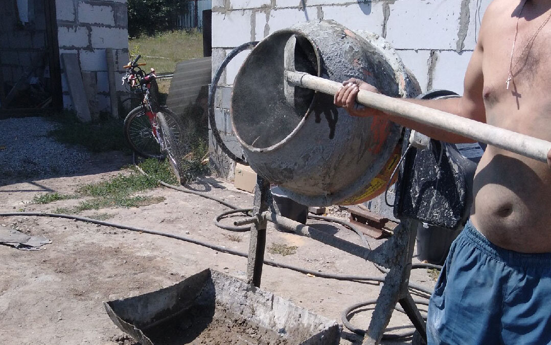 Добавляю цемент в бетономешалку.