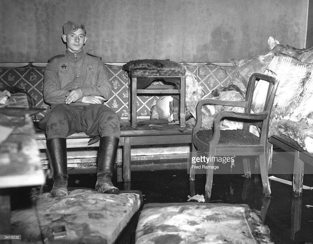 Советский солдат сидит на том самом диване, где слуга и адъютант фюрера обнаружили телa Гитлера и Евы Браун. Фото: Fred Ramage | gettyimages.com