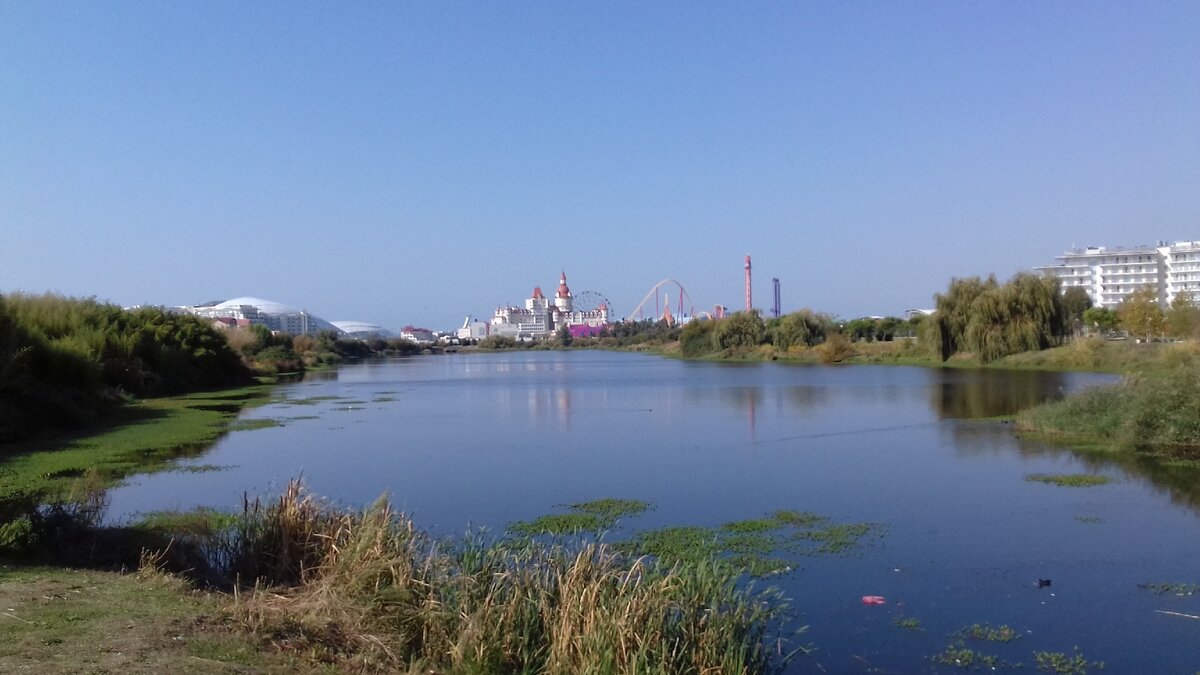 За озером виднеется стадион Фишт, отель Богатырь и парк аттракционов