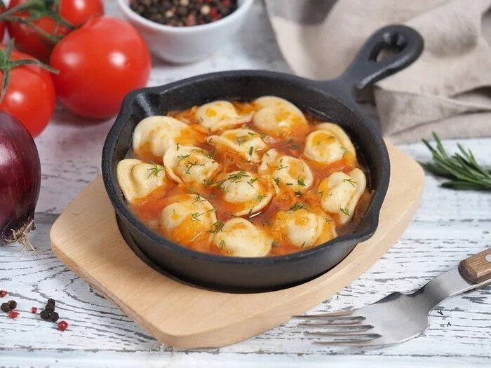 200 г готовых равиоли (мясных или грибных), 1 л растительного масла для жарки,
? мелко порубленной репчатой луковицы,
150 г грибов (белых, опят, шампиньонов, лисичек...),
60 мл белого сухого вина,
60 мл оливкового масла,
400 г кашицы из очищенных консервированных томатов,
1 ст. ложка рубленого тимьяна,
соль и перец.
Приготовление жареных пельменей
Готовим соус
Нагрейте кастрюлю с толстым дном на среднем огне,  разогрейте в ней оливковое масло.
Когда масло нагреется, обжарьте в нем, постоянно помешивая, лук, затем добавьте нарезанный чеснок, а через пару минут – грибы. Все тщательно перемешайте и влейте в кастрюлю белое вино и оставьте все вариться примерно на 5 минут.
Затем добавьте томатную кашицу, перемешайте, приправьте солью и перцем и оставьте на медленном огне на 10-15 минут, после чего снимите кастрюлю с огня.
Добавьте в соус свежий тимьян и измельчите все ручным блендером до примерно однородного состояния.
Жарим пельмени
Разогрейте растительное масло в большой кастрюле с толстым дном до достаточно высокой температуры. Поставьте рядом с плитой поднос, покрытый несколькими слоями бумажных полотенец.
Обжаривайте пельмени, постоянно их переворачивая, пока они не станут коричневыми. Это займет примерно минуту.
Не выкладывайте во фритюр сразу все пельмени, разделите их примерно на 3 части и обжаривайте каждую отдельно.
Готовые пельмени выкладывайте на бумажные полотенца, чтобы дать излишкам масла стечь и впитаться.
Подавайте жареные пельмени горячими вместе с соусом.