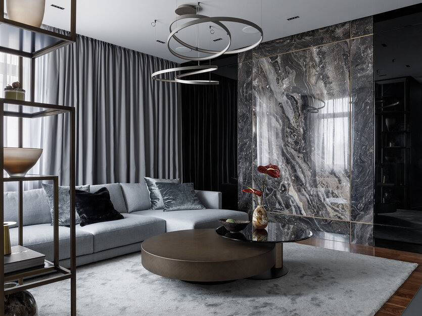 Гостиная. Диван, B&B Italia. Журнальный столик, подвесные светильники у дивана, Cattelan Italia. Доминанта пространства — стена в отделке слэба натурального мрамора Arabescato Orobico Grigio, чёрного стекла и зеркала дымчатого цвета. Встроенные светильники, Prolicht. Стеллаж из латуни и черного стекла выполнен на заказ по проекту Александра Левицкого. Ковёр, бельгийская компания LimitedEdition.