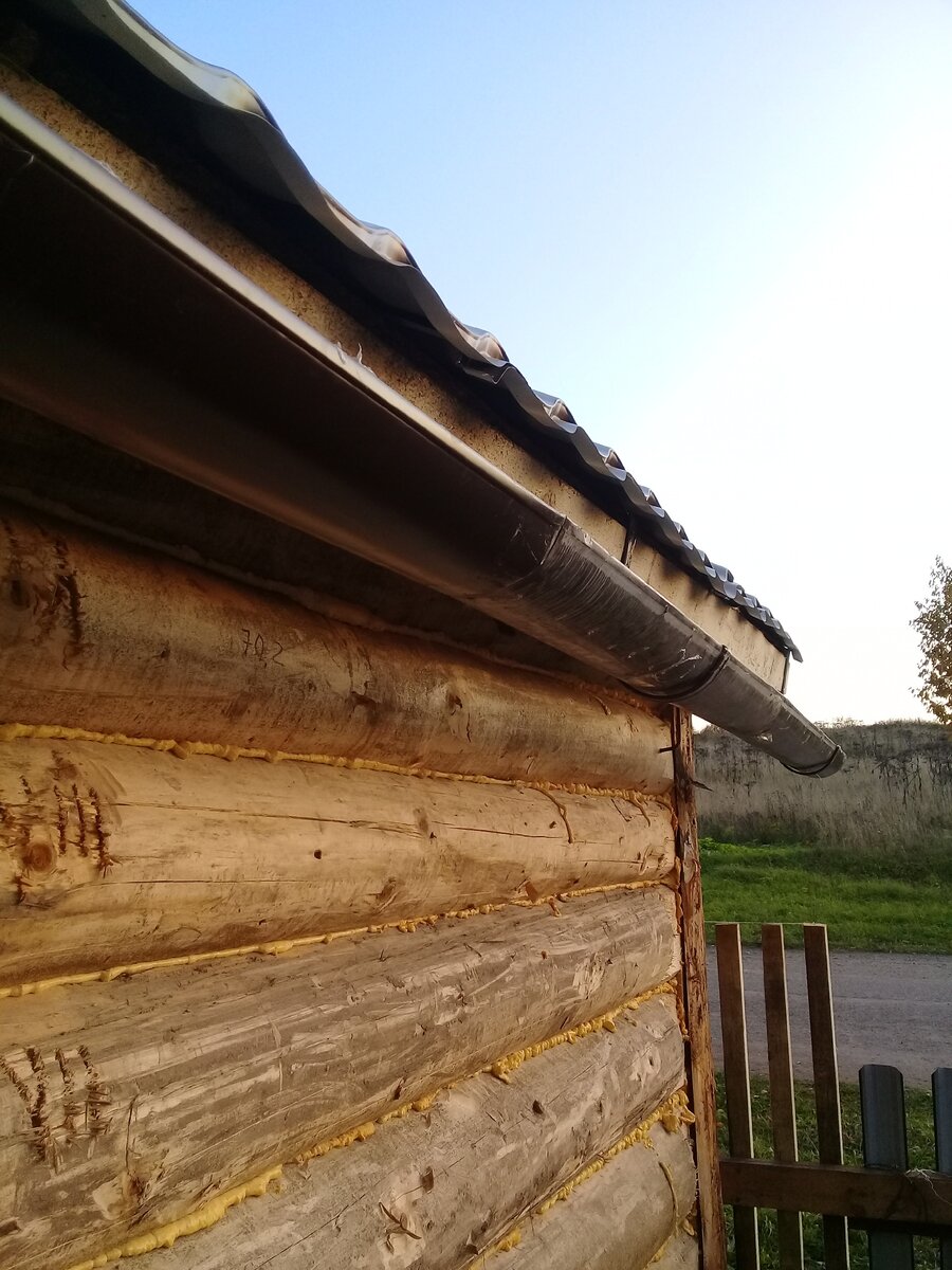 Под крышей бани. Желоб прикреплён с уклоном на улицу.