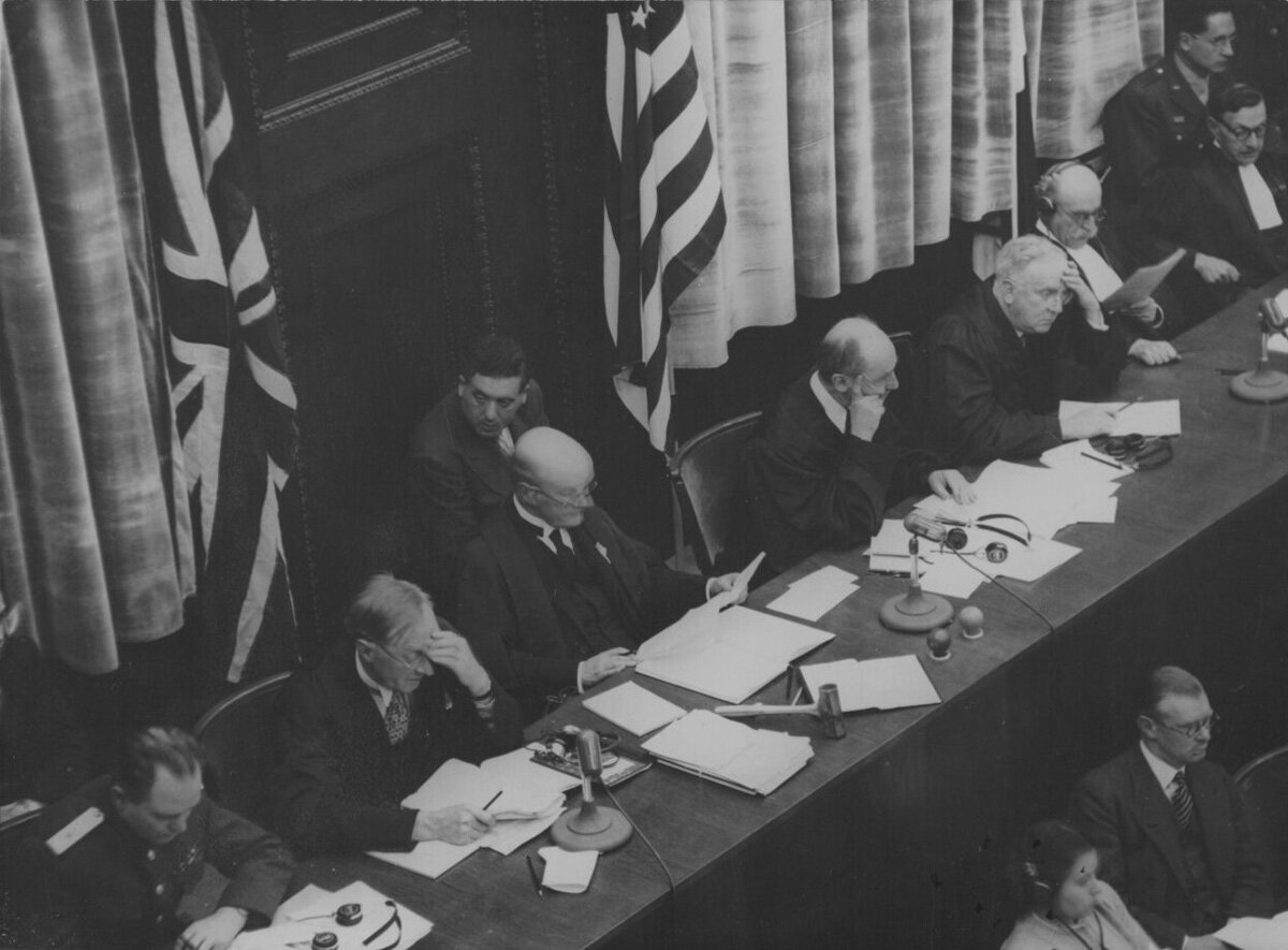 Судьи Нюрнбергского трибунала за работой в зале суда. Слева направо: генерал-майор юстиции Иона Тимофеевич Никитченко, Норман Биркетт, Джеффри Лоуренс, Фрэнсис Биддл, Джон Паркер, Анри Доннедье де Вабр и Робер Фалько.