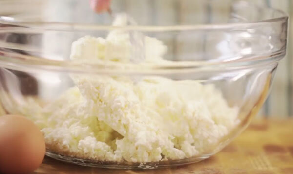 В емкость выкладывают творог, вбивают в него яйцо. Ингредиенты растирают при помощи ложки или толкушки. 