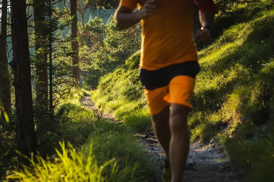 Trail man. Бегун в горах. Медленный бег. Бегун в хвойном лесу. Бег от первого лица.