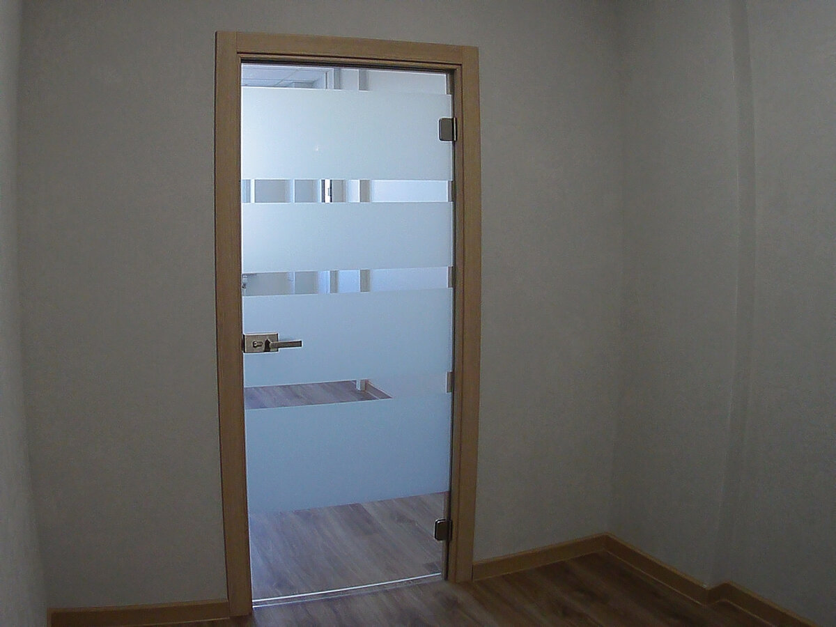 Офис в Нижнем Новгороде. Стеклянная дверь в комплекте с деревянной коробкой. Бесцветное закаленное стекло, матовая архитектурная пленка. Фабричная фурнитура для стеклянной двери в деревянной коробке -  с хромированным покрытием. Деревянная коробка, экошпон.