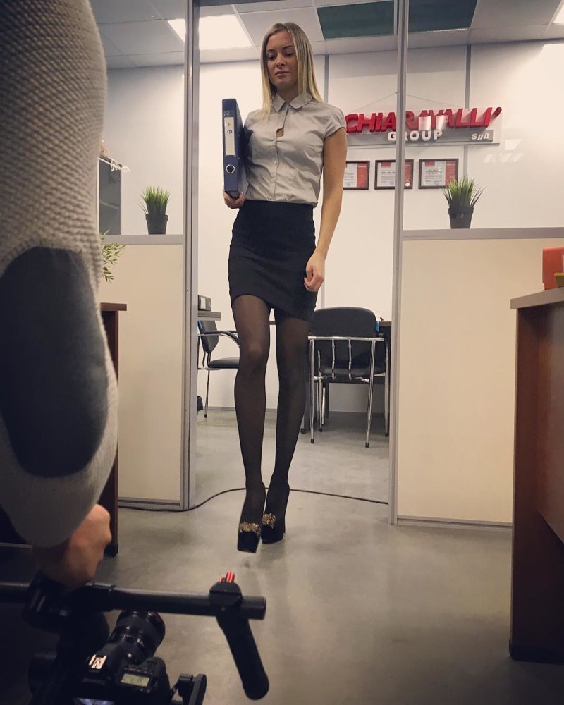 Сексуальная секретарша в блузке и мини-юбке, сидя в офисе