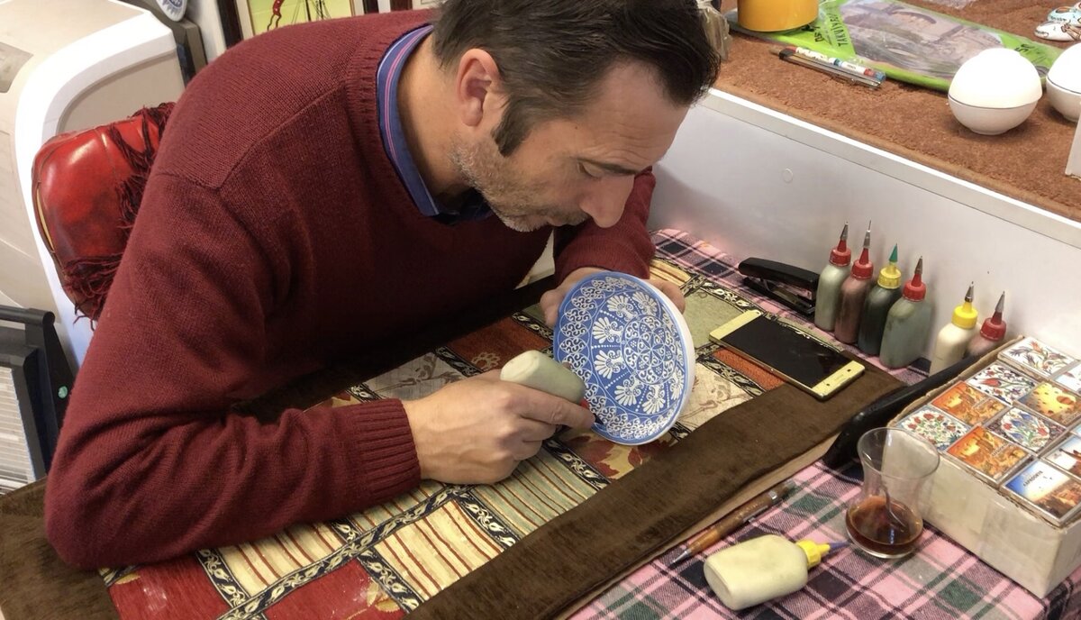 Мастер рисует узоры на посуде