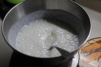 Сперва нужно прогреть жирный кефир до чуть теплого состояния или комнатной температуры. Оладьи, приготовленные на теплом кефире, получаются намного пышнее. К кефиру следует добавить соду. Нужно перемешивать заготовку теста до тех пор, пока кефир не начнет пузыриться. Замес теста для оладий следует производить ложкой, миксер не понадобится. Всыпать соль, ваниль и сахар. Перемешать компоненты.