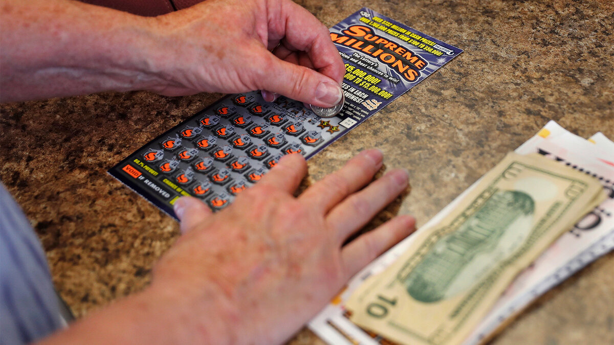 Человек стирает лотерейный билет.