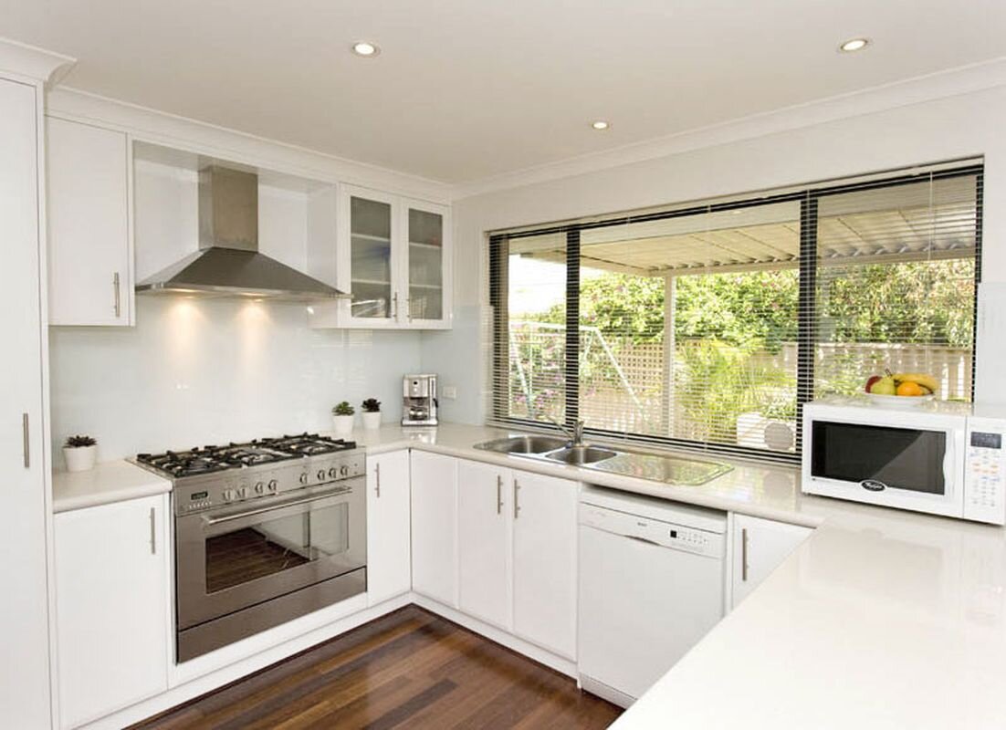 П-образная белая кухня в стиле минимализм с деревянным полом.