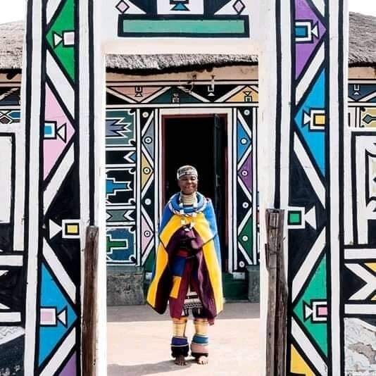 Рисовать у меня в сердце и в моей крови », - говорит Эстер Малангу. Возможно, она не умеет читать или писать, никогда не ходила в школу, но она родилась художницей. В возрасте 83 лет она считается национальным достоянием. Она посвятила свою жизнь тому, чтобы поделиться своим культурным наследием с миром с помощью своих ярких геометрических и симметричных абстрактных картин и фресок в традициях ндебеле. Среди самых известных ныне живущих художников Южной Африки, выставлявшихся в самых уважаемых музеях мира и считающих знаменитостей Ашера, Swizz Beatz, Джона Ледженда и Опру Уинфри коллекционерами, она была первым человеком, перенесшим освященный веками стиль живописи ндебеле из стена на холст, эффективно продвигая и сохраняя этот вид искусства. Благодаря продажам ее работ в размере от 3000 до 30 000 долларов и комиссионным вознаграждениям за росписи, она проводит большую часть своего времени, работая над общественными проектами в деревне Мабхоко в провинции Мпумаланга, обучая мальчиков и девочек рисованию и вышивке бисером - техникам, переданным ей от матери и бабушка - чтобы они однажды могли учить своих детей, открыв собственную художественную школу на заднем дворе ее дома. Одетая в красочные традиционные регалии с золотыми кольцами на шее, руках и ногах, которые никогда не снимаются, ожерельями, браслетами, серьгами и ободками из бисера, она постоянно путешествует, чтобы распространять свою культуру по всему миру, чтобы гарантировать выживание искусства ндебеле.