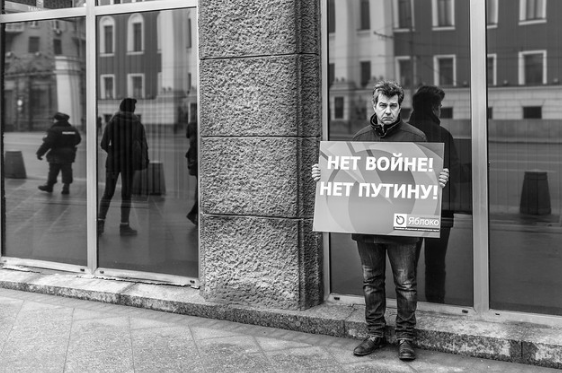 Одиночный пикет представителя партии "Яблока" - типичное проявление детского либерализма, нездорового. В витрине отражается наряд полиции: этих бедолаг пока не трогают