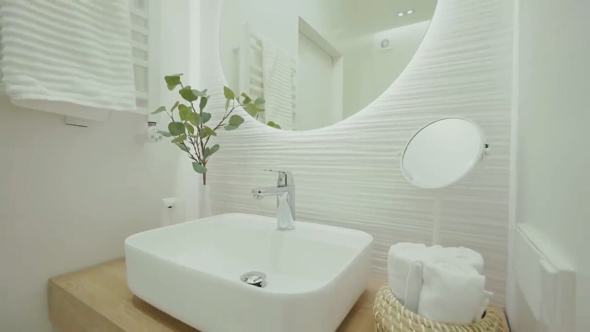 Ванная комната в белом цвете с зелёным акцентом.