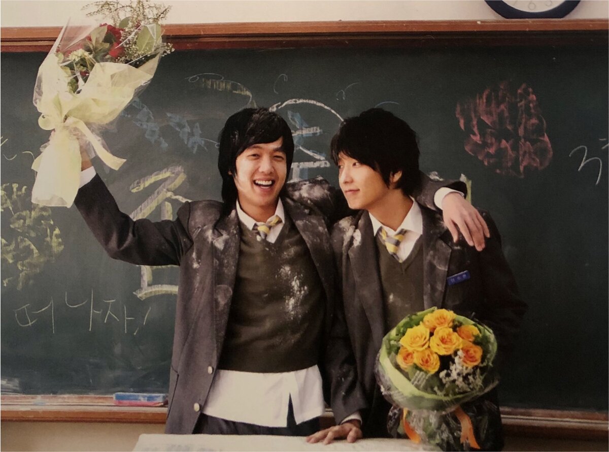 Начнем со средней школы. Или это старшая? Трудно разобрать, на самом деле. Мы уже видели выпускные школьные фото Су Хёна и Минги. Видели, что Су Хён уже в те молочные времена был двольно "внутри себя" парнем. Ну, а Минги как обычно - душа нараспашку. Также у Минги немного покровительственная поза. Ну как же. Он сын своих родителей, живет в своей стране. А Су Хён, между прочим, родился в Лондоне и считается ребенком дипломата 🤔