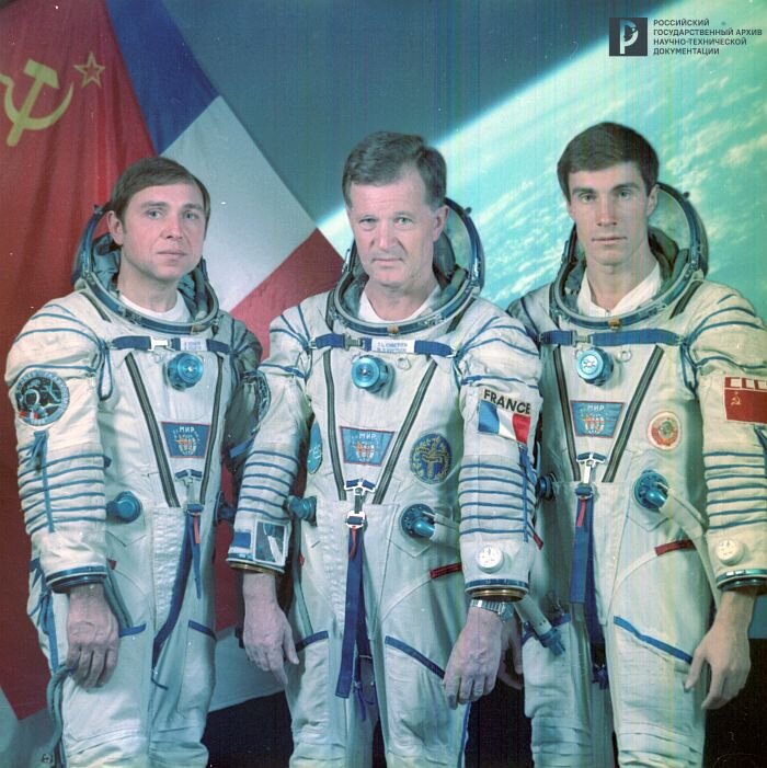 Советско-французский экипаж космического корабля «Союз ТМ-7»: А.А. Волков, Ж.-Л. Кретьен и С.К. Крикалев на фоне государственных флагов. РГАНТД. Арх. № 1-4997 цв.