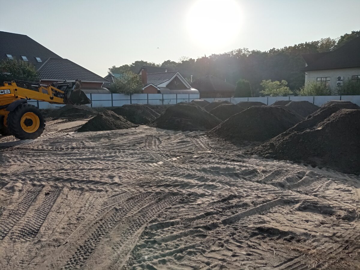 Планировка грунта экскаватором-погрузчиком.