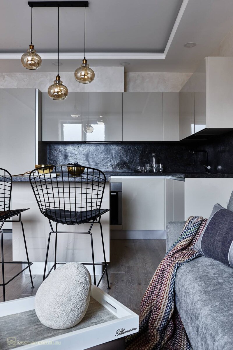 Вид на зону кухни с глянцевыми фасадами мебели со стороны гостиной