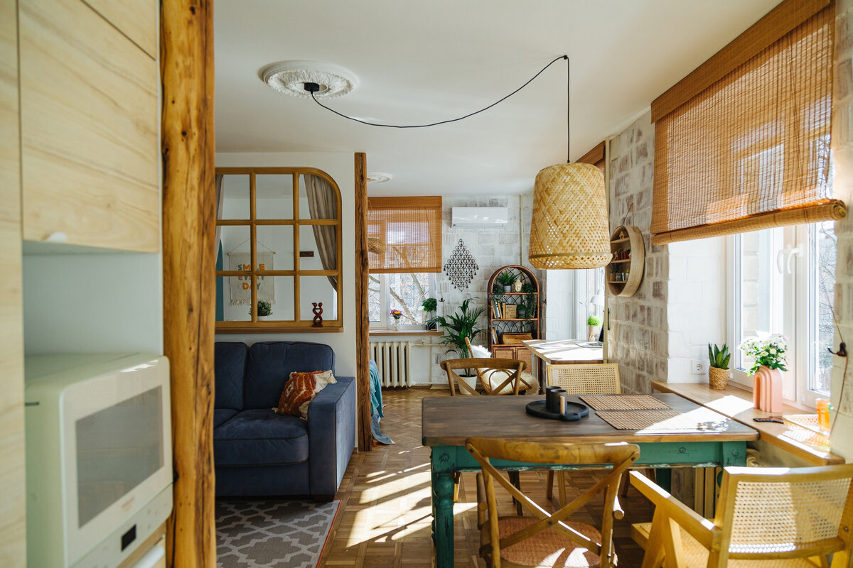 Вид со стороны кухни. Стена между двумя комнатами частично снесена. Теперь это как бы и общее пространство, и в то же время зоны с разными функциями — для обедов и разговоров (стул и диван), для сна и работы (кровать с рабочим местом)