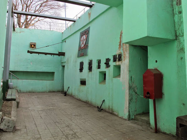 Вход в орудийный блок № 1 оформлен в виде заглубленного дворика в который выходит два проема сквозника. На стене оригинальная памятная доска в честь окончания строительства батареи с надписью "ВЛКСМ КИМ XV ЛЕТ Х-1933". 