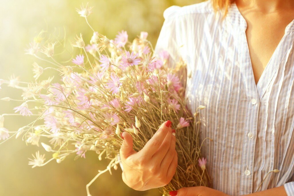 Будет просто сиять и. Женская рука с цветком. Женщина с букетом полевых цветов. Полевые цветы в руках. Цветы в руках женщины.