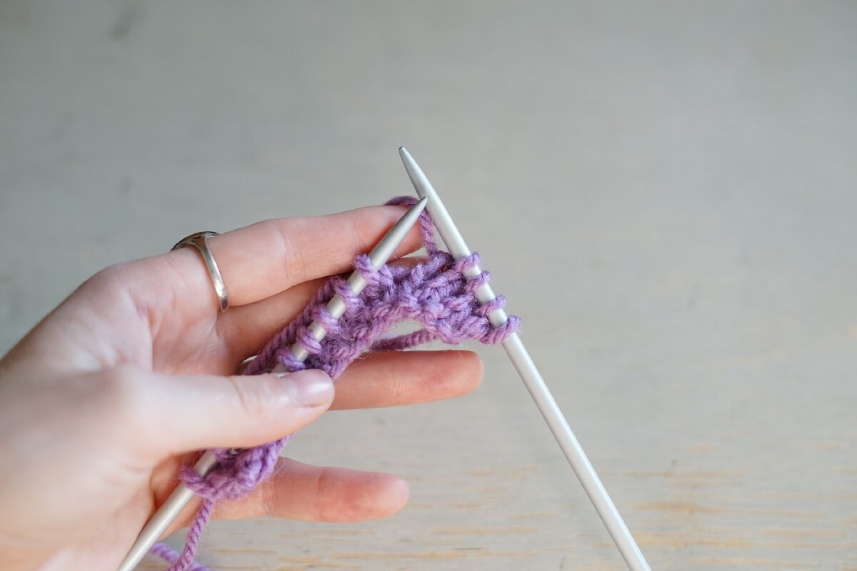 Нить вязания находится за спицами.
