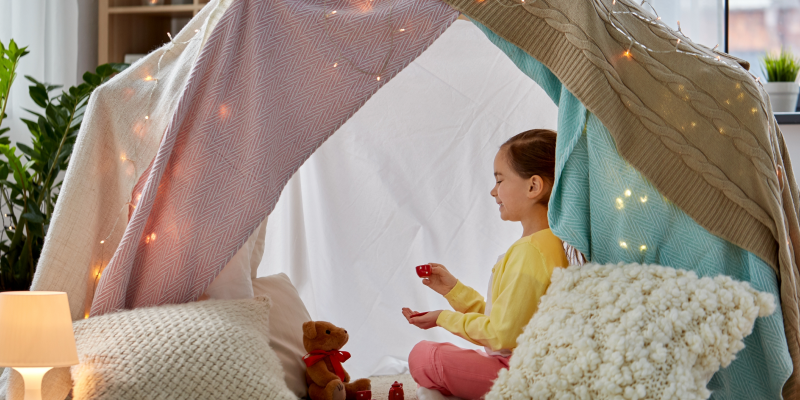 "Самодельный" домик из одеял и подушек, украшенный гирляндой