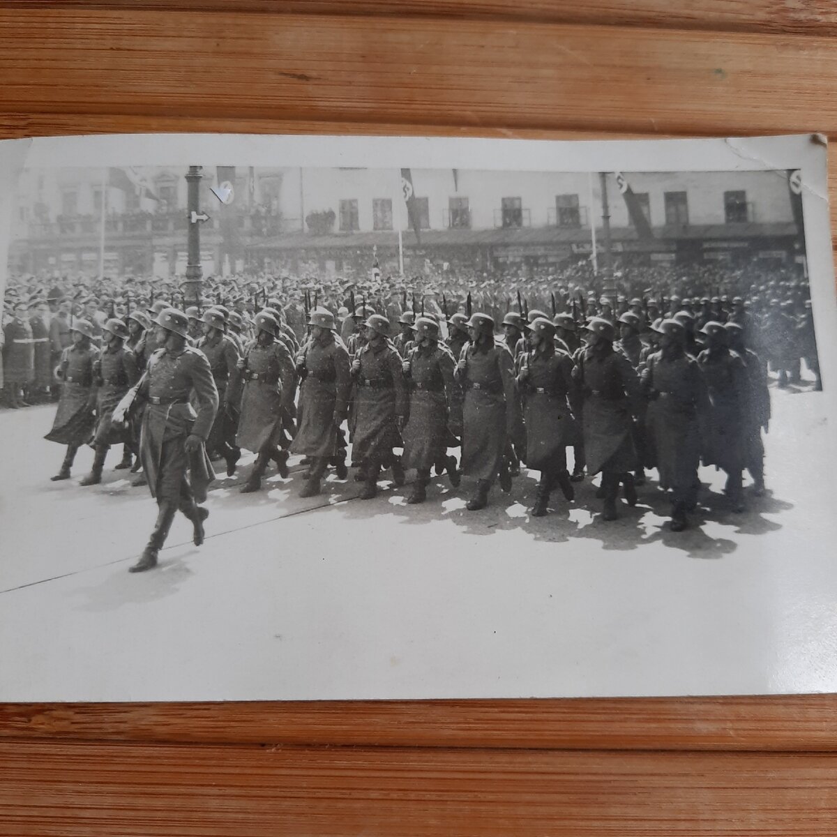 Листайте галерею вправо. Парад на улице города. Наблюдает публика, все увешано флагами.