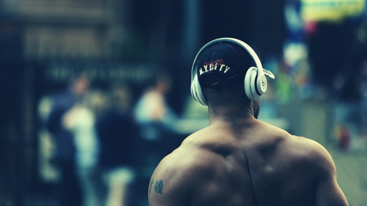 Занимаются спортом под музыку. Наушники тренажерный зал. Наушники для тренировок. Наушники в зале. Спина спортсмена.