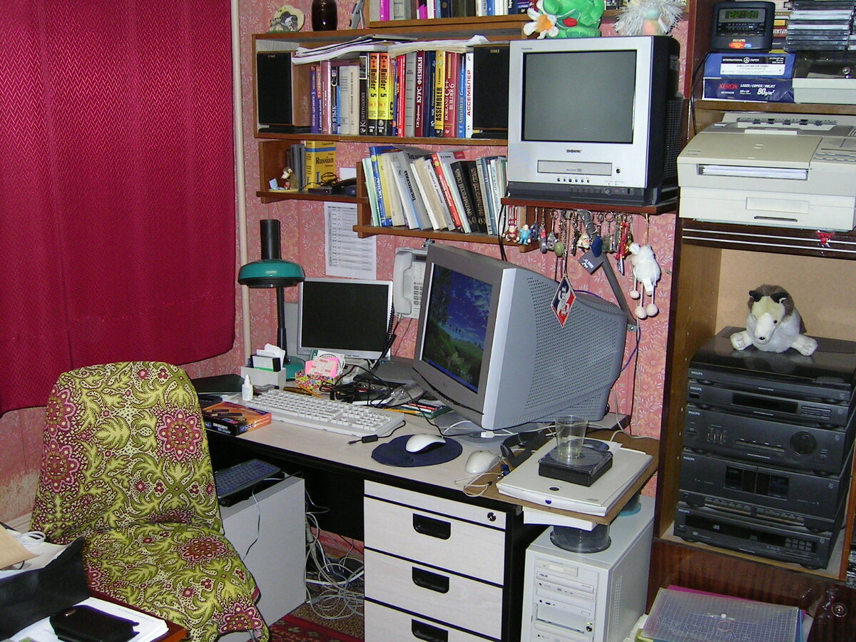 Основной рабочий стол уже с двумя системниками, монитор ещё ЭЛТ, зато 19". Второй системник довольствовался 14", но уже ЖК-монитором. Модный по тем временам музыкальный центр уже использовался как аудио система 2.0 для компа. Литература на самодельных полках характерная...
