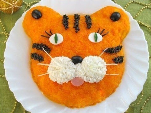 🐯 Салат "Тигренок"
Ингредиенты: картофель - 400 гр, вареная колбаса - 200 гр, огурцы - 200 гр, лук-порей или репчатый лук - 150 гр, яйца - 3 шт, морковь - 400 гр, майонез, соль, маслины (для украшения).
Готовим: Картофель и морковь отвариваем до готовности, остужаем, чистим. Картофель и морковь натираем на мелкой терке. Колбасу и огурцы нарезаем мелкими кубиками. Лук-порей мелко крошим (репчатый лук нарезаем кубиками, заливаем кипятком, оставляем на 15 минут, затем промываем в холодной воде). Яйца варим вкрутую, остужаем, чистим и натираем на мелкой терке (белок от одного яйца оставляем для украшения).
На дно плоского блюда выкладываем картофель, придаем форму головы тигра и смываем майонезом. На картофель выкладываем слоями, смазывая каждый слой майонезом и подсаливая, следующие ингредиенты: вареная колбаса, огурцы, лук, яйца. Последним слоем выкладываем морковь, покрывая весь салат.
Из яичного белка делаем глазки и щечки тигренка. Мелко нарезаем около 6-7 маслин. Делаем из них нос и ресницы. Из огурца - зрачки. Из колбасы - рот. Из оставшихся нарезанных маслин выкладываем полоски. Усы можно сделать из белой части лука порея.
Приятного аппетита!