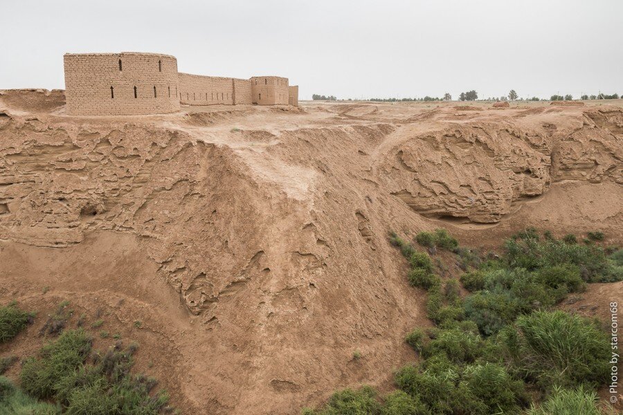 Вид с востока на восстановленную внешнюю стену нижнего города Кампыртепы через овраг (джар). На переднем плане восточная угловая башня